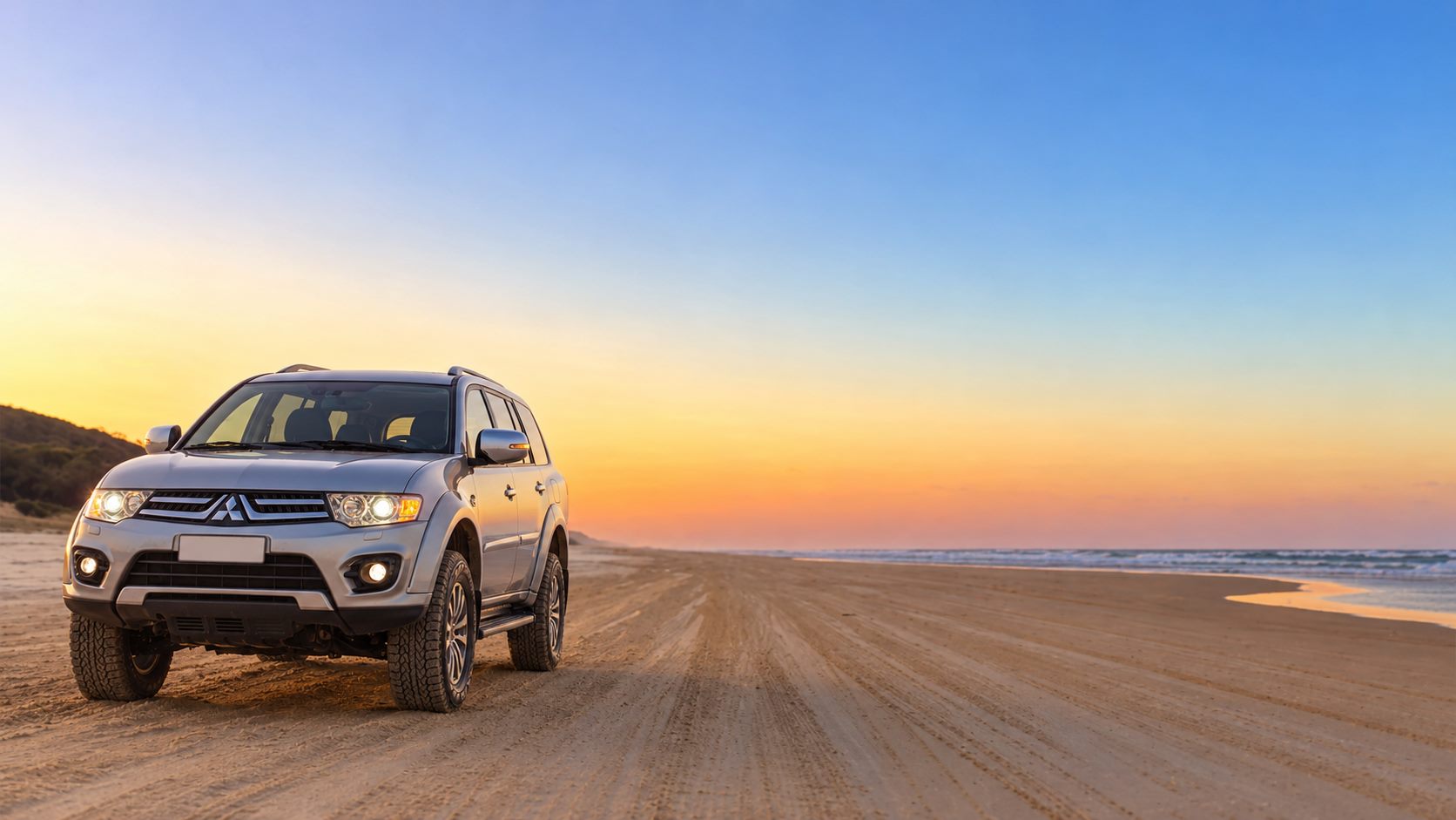 Veículo 4x4 na praia ao pôr do sol